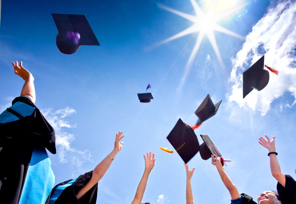 new graduates celebrating graduation and throwing caps in the air