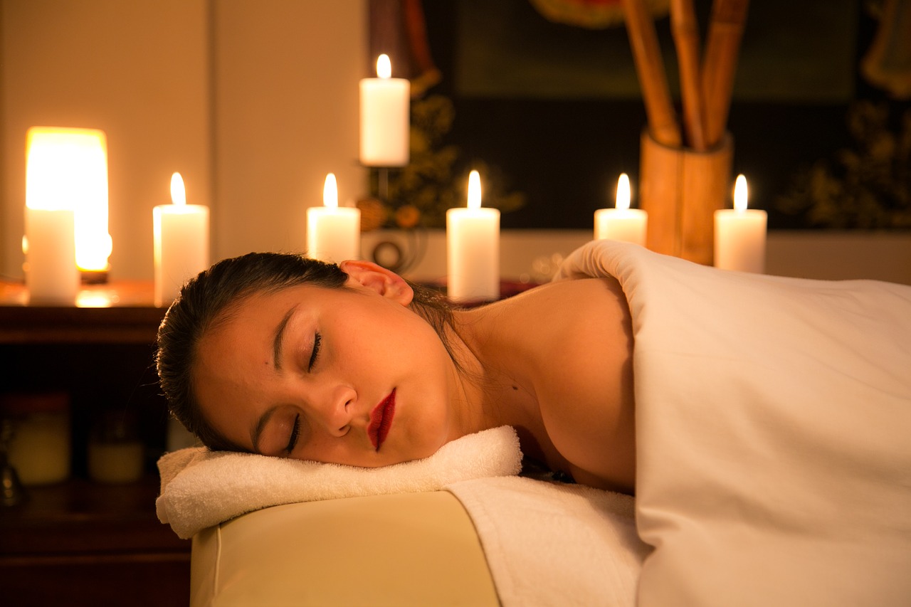 relaxed woman on massage table, surrounding by candles