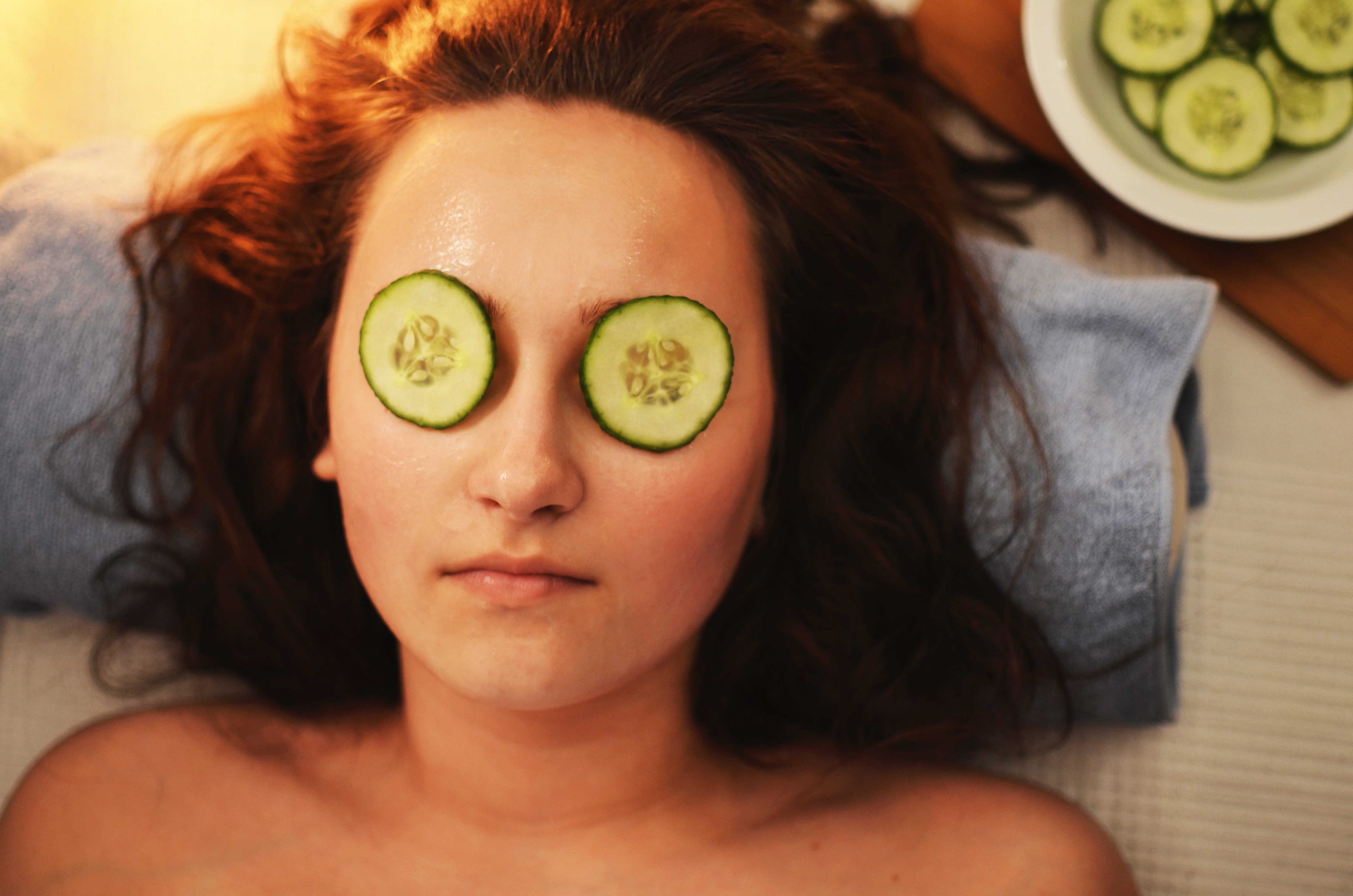 woman relaxing with sliced cucumbers on her eyes