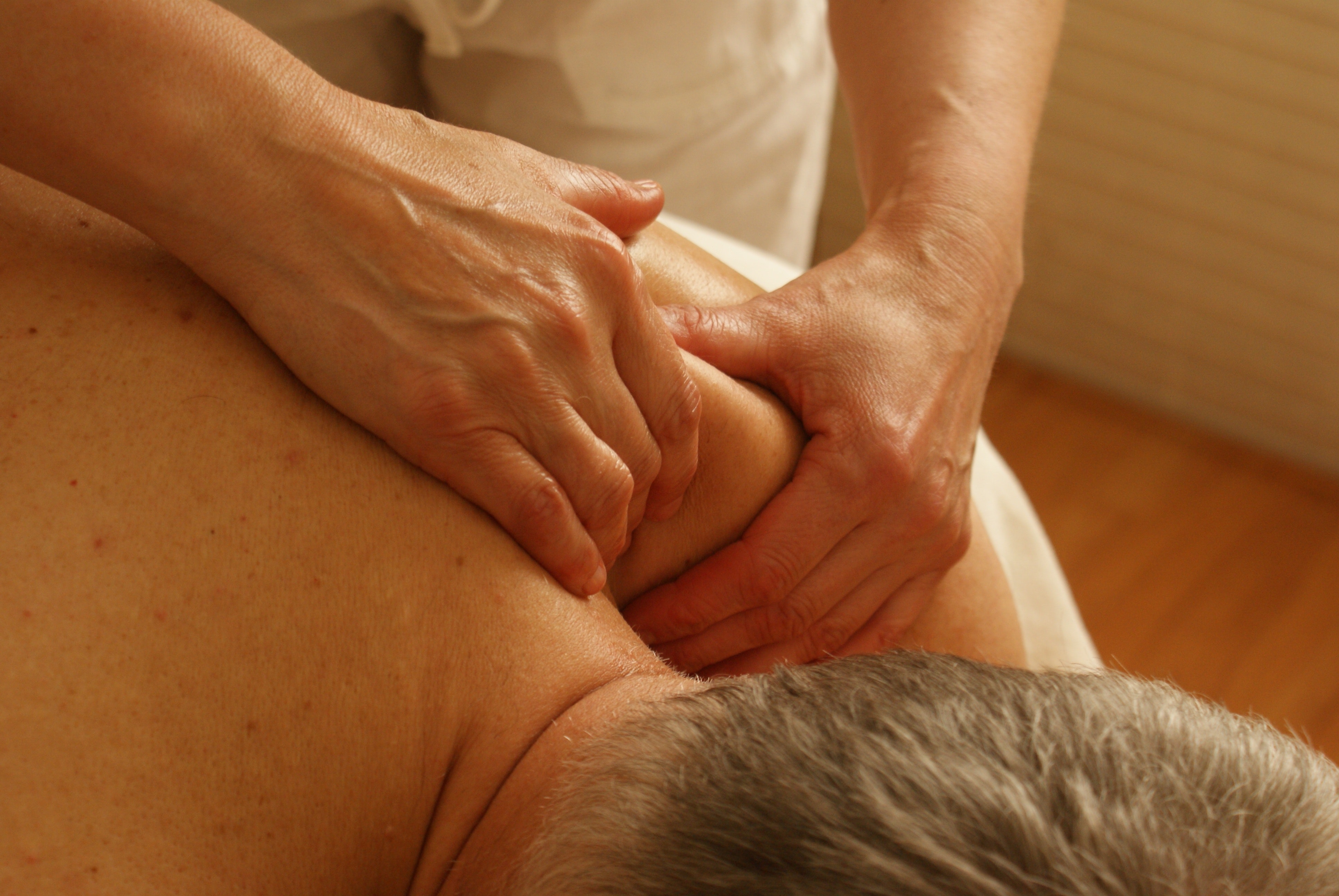 Salt and pepper haired man getting deep tissue shoulder massage at Urban Oasis Day Spa