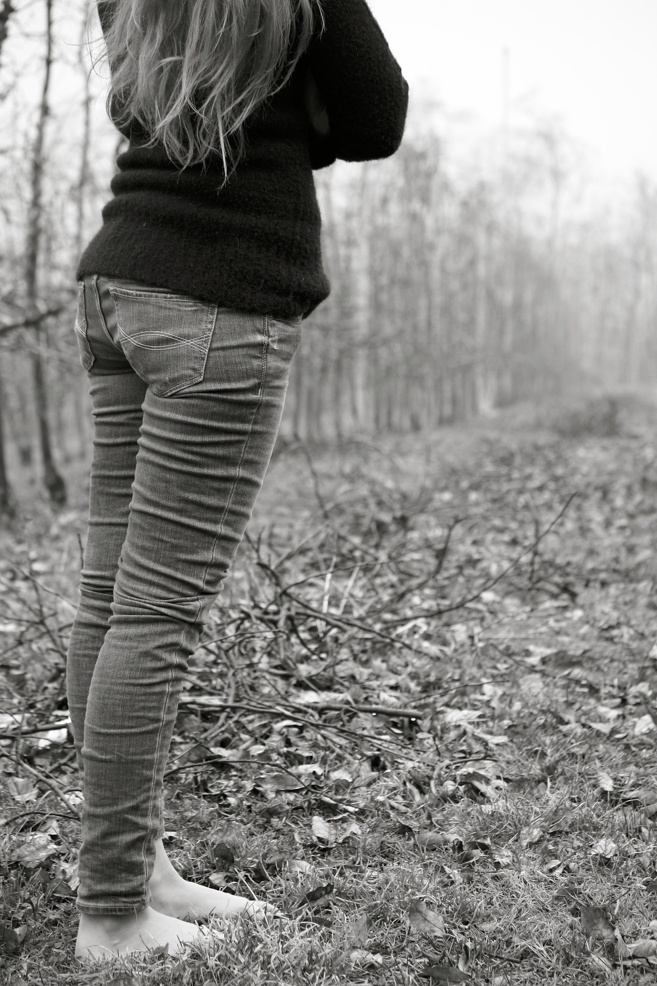 black and white photo of a woman standing in a forest in autumn