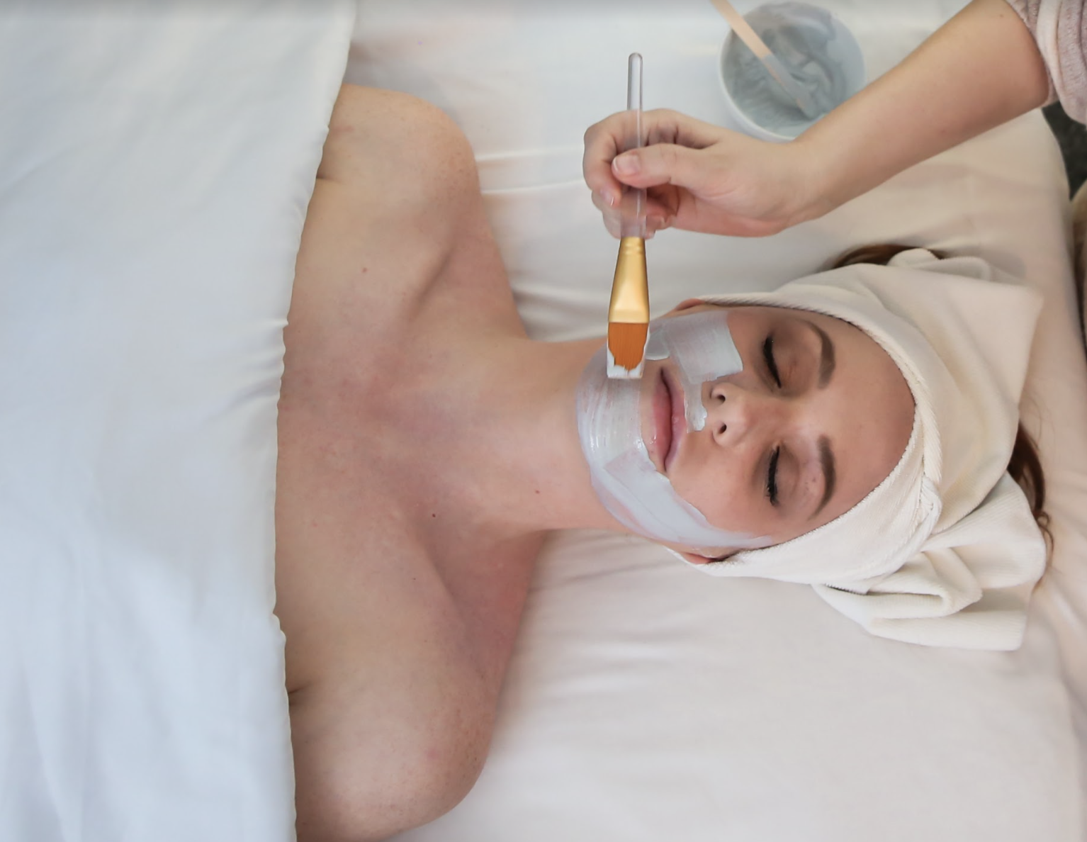 Woman receiving a clay face mask at Urban Oasis Day Spa