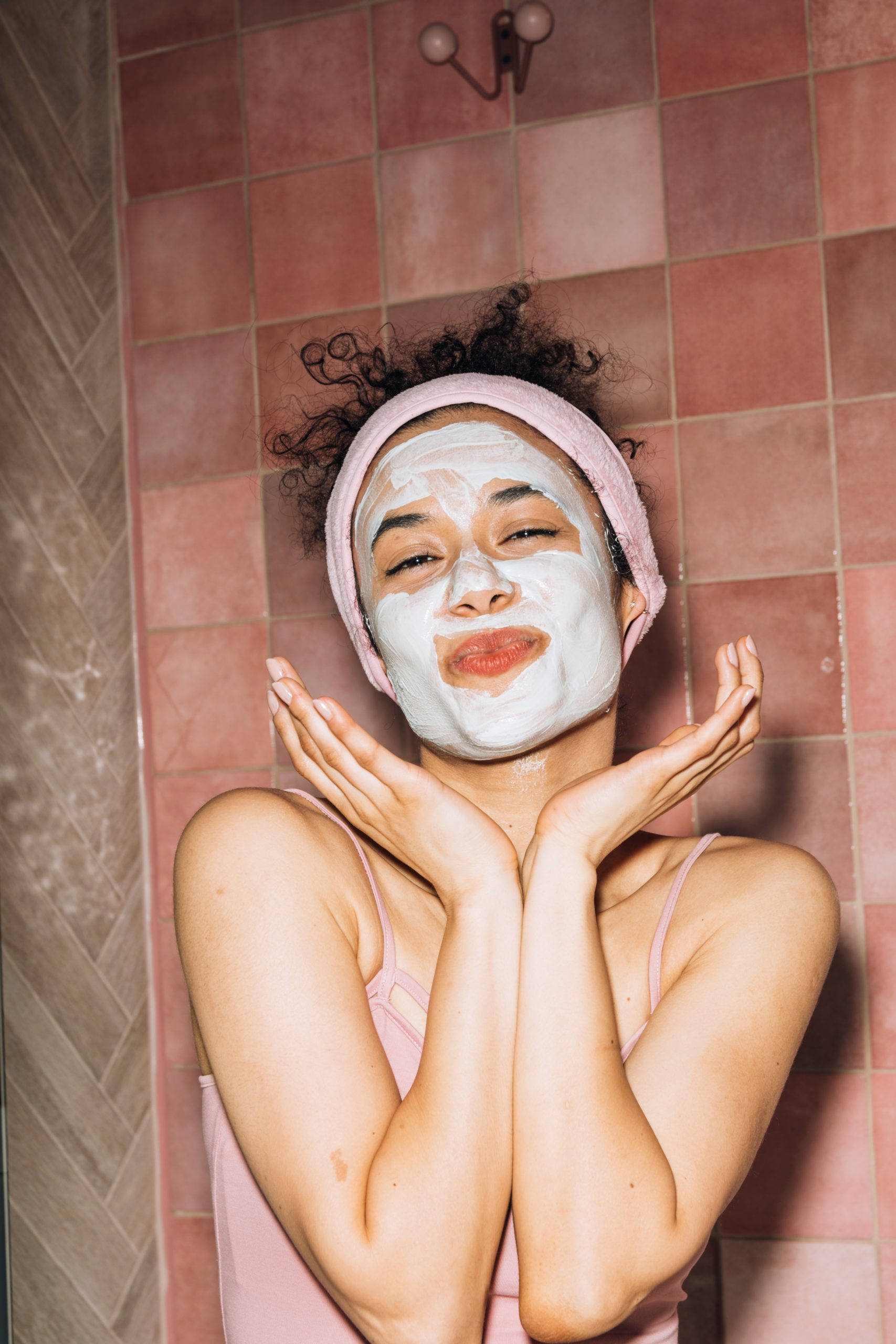 Happy woman making a cute face with her clay face mask on