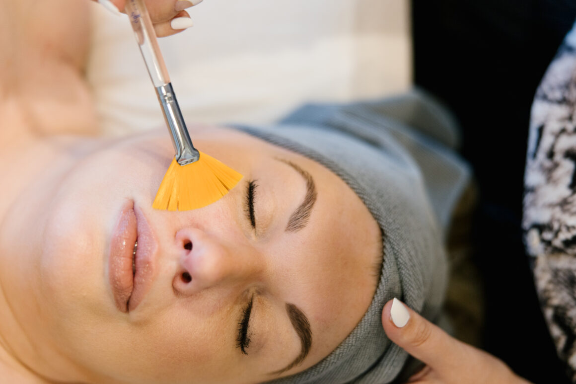 A woman relaxing with her eyes closed while receiving a Better Than Botox anti-aging facial at a luxury spa. A skincare specialist gently applies a treatment to her face, promoting a youthful, radiant glow. The setting is serene and calming, enhancing the experience of non-invasive skin rejuvenation.