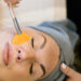 A woman relaxing with her eyes closed while receiving a Better Than Botox anti-aging facial at a luxury spa. A skincare specialist gently applies a treatment to her face, promoting a youthful, radiant glow. The setting is serene and calming, enhancing the experience of non-invasive skin rejuvenation.