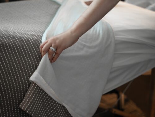 Person pulling back the spa bed sheets, preparing for a massage session at Urban Oasis Nashville