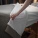 Person pulling back the spa bed sheets, preparing for a massage session at Urban Oasis Nashville