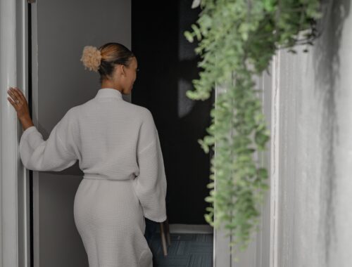 A woman entering a softly lit spa treatment room at Urban Oasis Nashville, preparing to enjoy a relaxing massage or facial with a free aromatherapy or CBD upgrade during the Thanksgiving spa special.