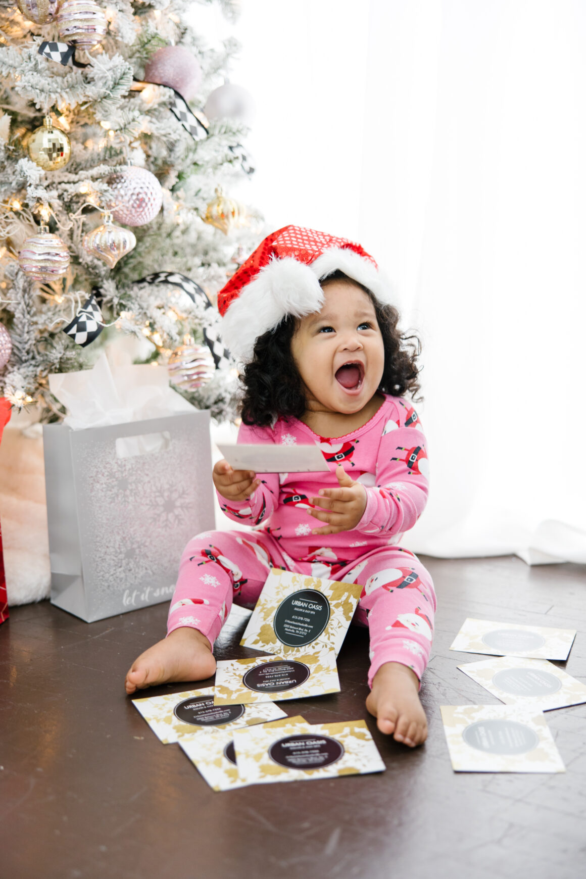 Excited baby laughing with spa gift cards from Urban Oasis Nashville, promoting the holiday Black Friday and Small Business Saturday spa sale.
