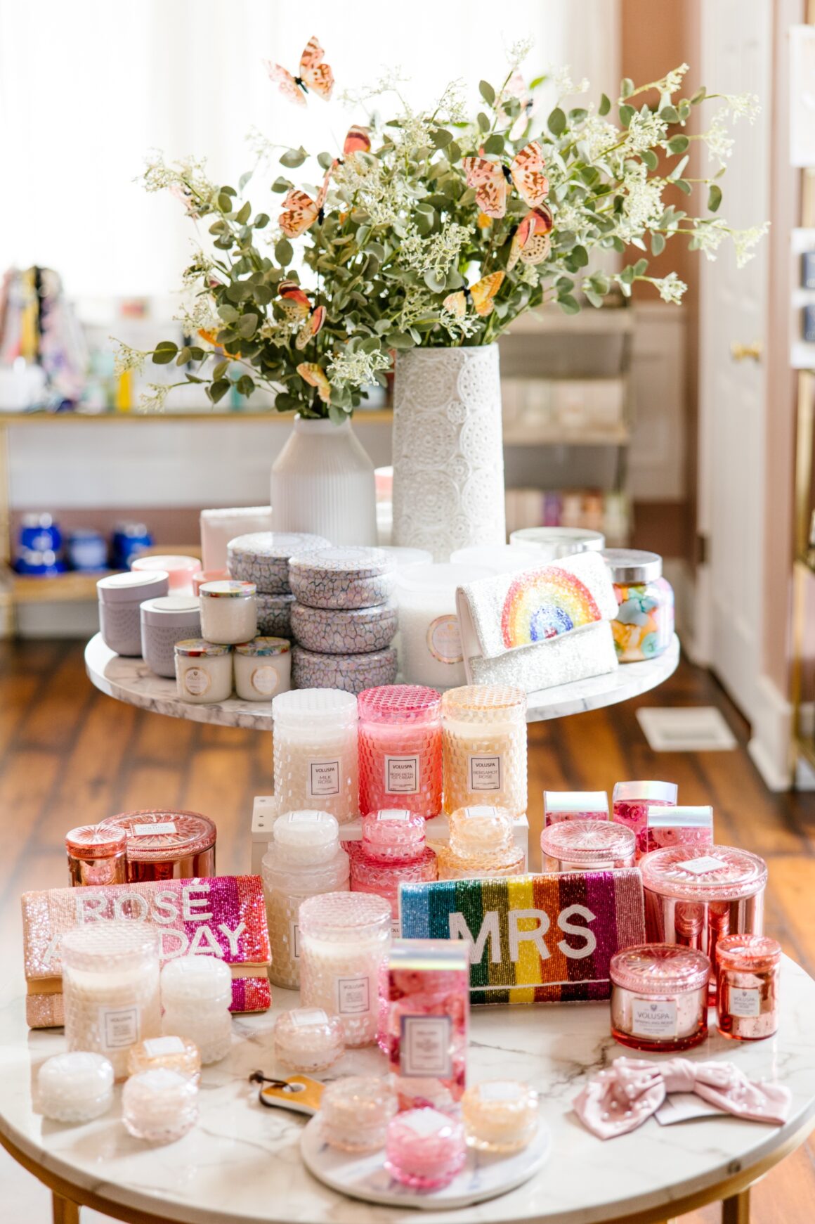 Luxury spa retail display featuring colorful Voluspa candles, gift boxes, rainbow clutches, and self-care accessories arranged on a marble table at Urban Oasis Nashville.