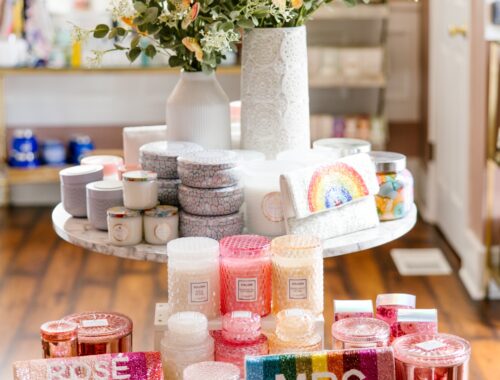 Luxury spa retail display featuring colorful Voluspa candles, gift boxes, rainbow clutches, and self-care accessories arranged on a marble table at Urban Oasis Nashville.