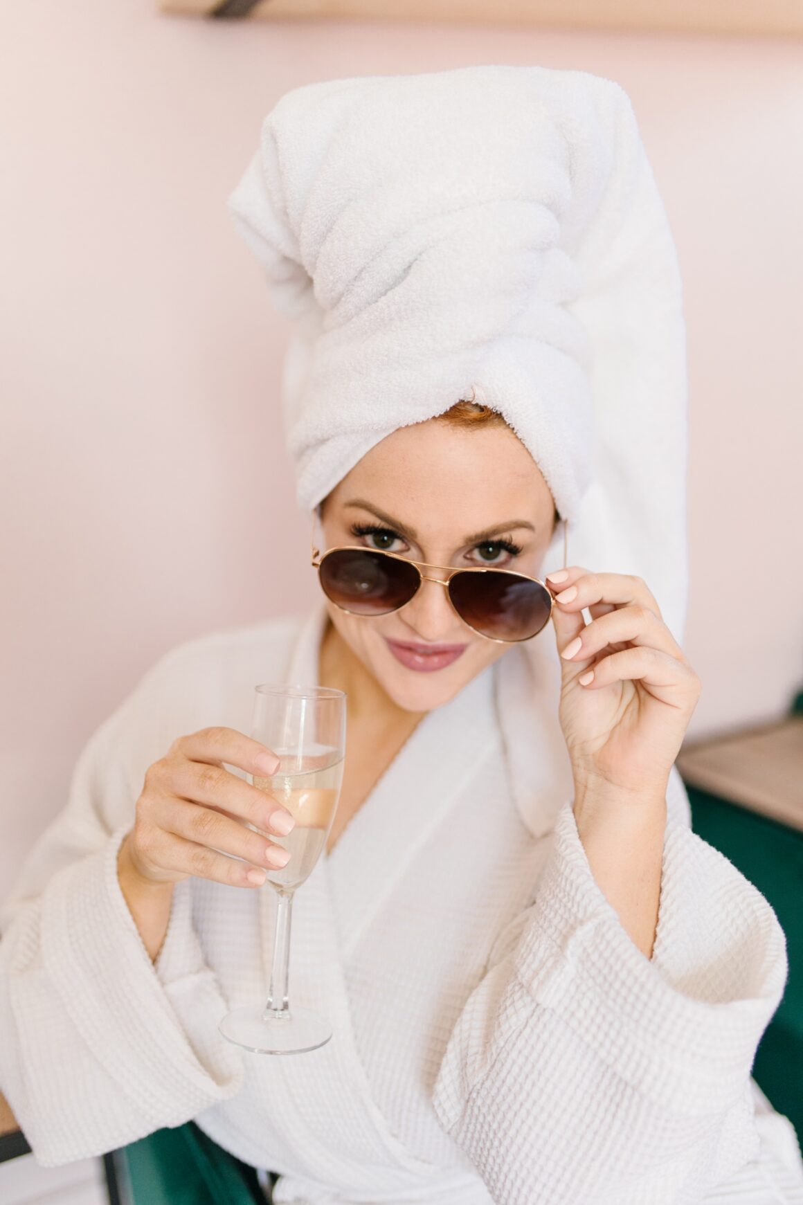 Woman in a white spa robe with a towel-wrapped head enjoying champagne during a relaxing spa day in Nashville