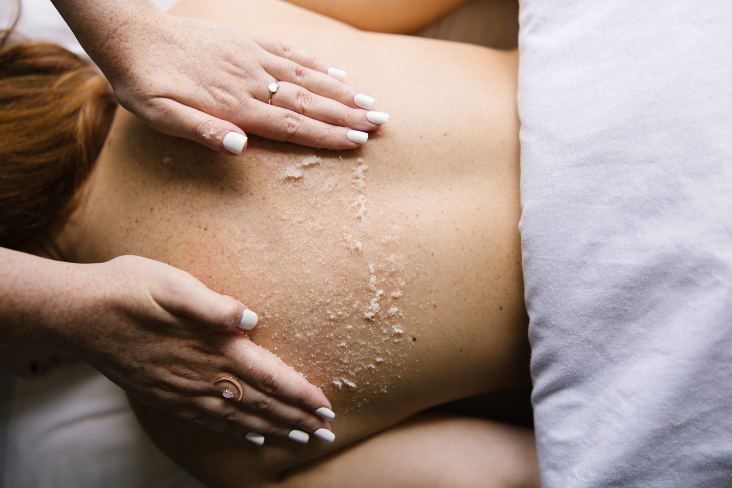 Spa therapist applying an exfoliating body scrub during a relaxing body polish treatment at Urban Oasis Nashville day spa.
